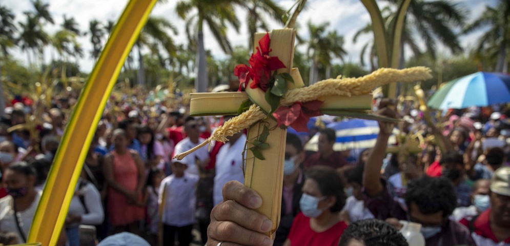 hombre sostiene una cruz de palma durante la misa del Domingo de Ramos