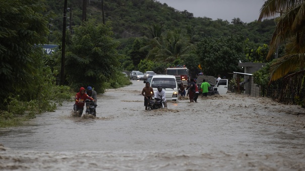 Personas cruzan con dificultad la carretera que se encuentra inundada producto de las intensas lluvias.