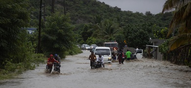 Personas cruzan con dificultad la carretera que se encuentra inundada producto de las intensas lluvias.