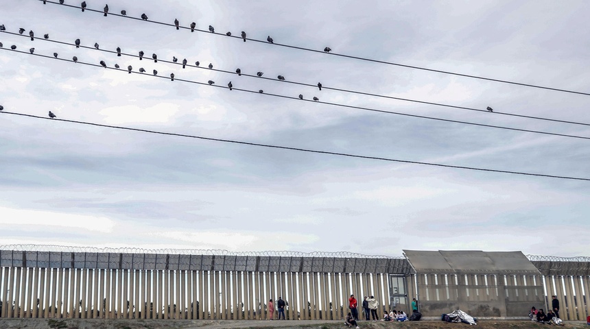 Migrantes permanecen en el muro fronterizo