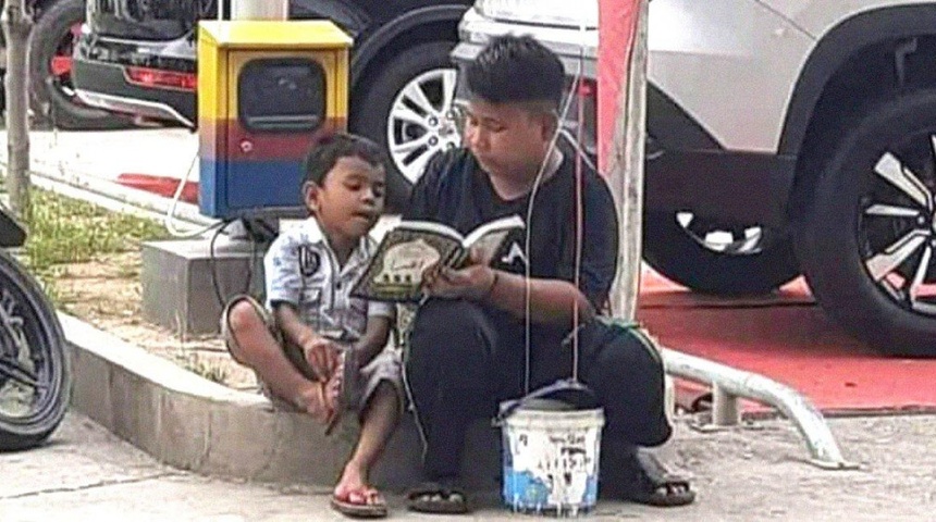 Un niño le enseña a leer a su hermano en su descanso de venta ambulante de globos y mascarilla