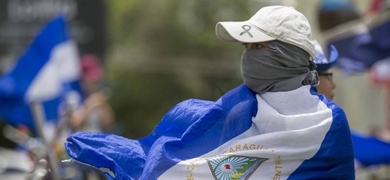 Una joven con la cara tapada y la bandera de Nicaragua